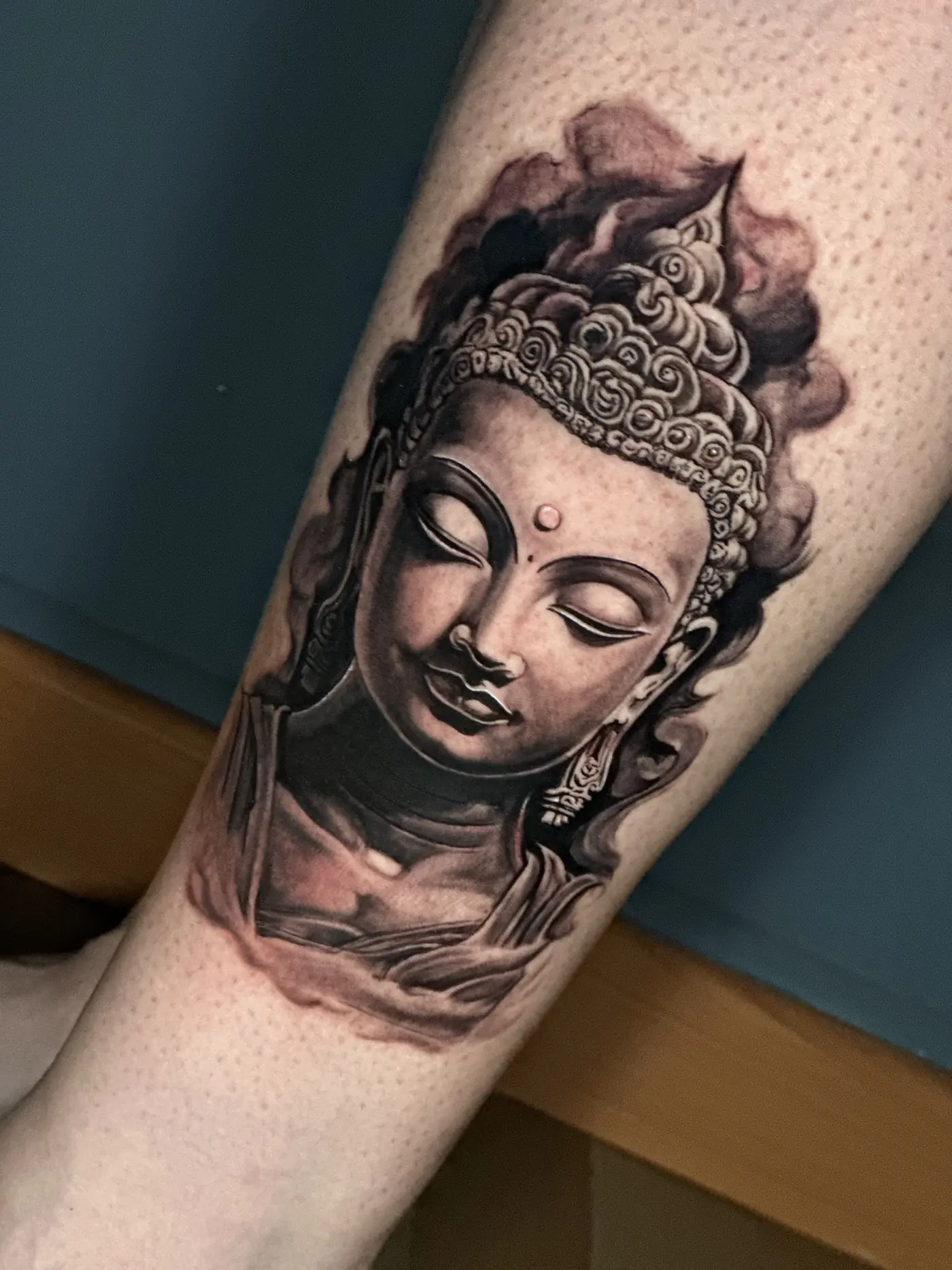 Tatuaje realista en blanco y negro de la cabeza de un Buda en la pantorrilla, hecho en Cartagena