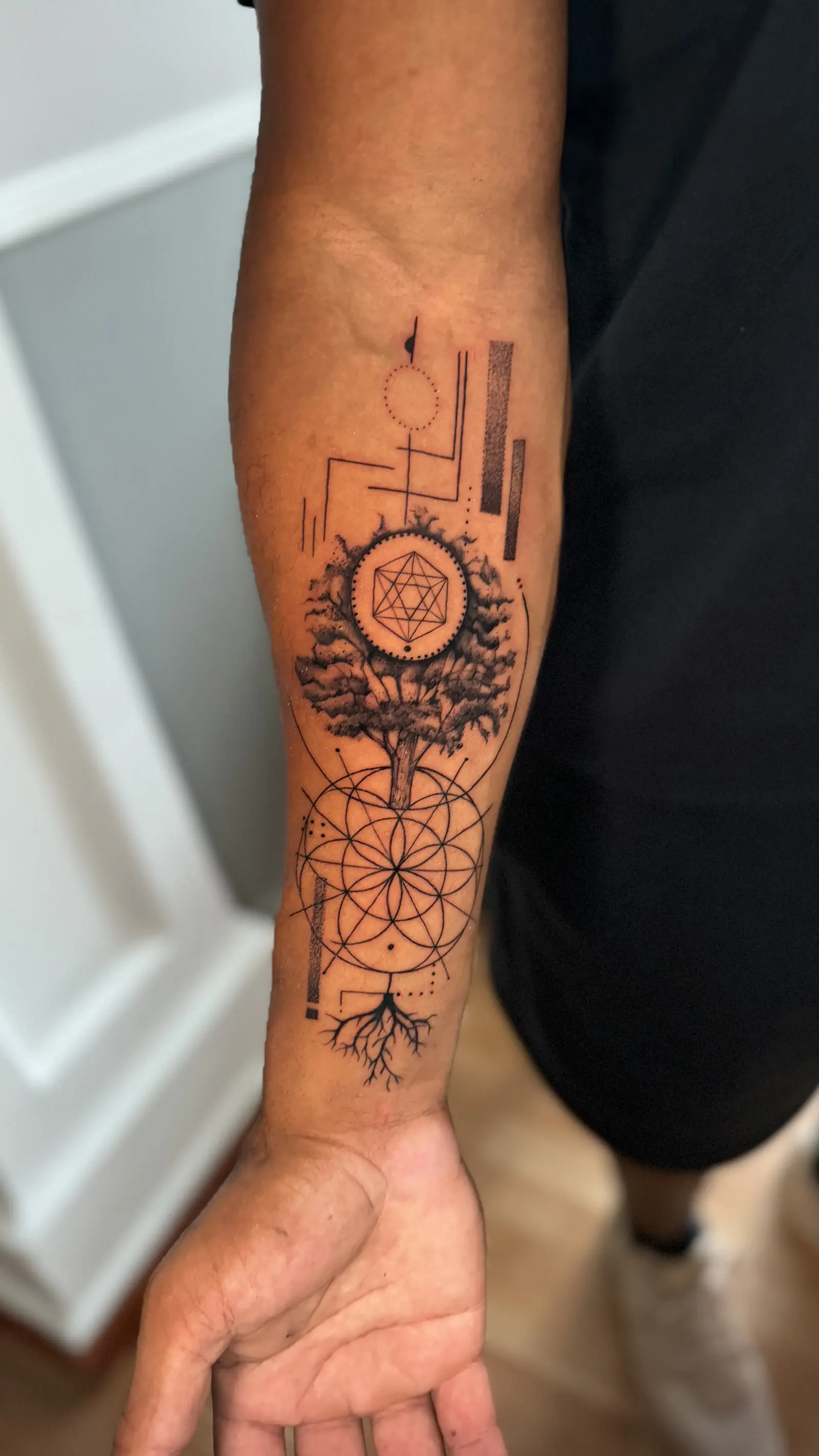 Tatuaje geométrico de un árbol con círculos de geometría sagrada en el antebrazo, hecho en Cartagena