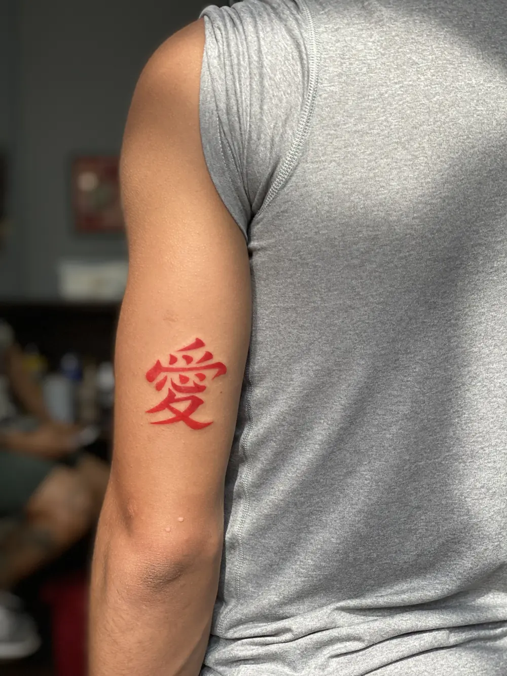 Tatuaje japonés en rojo del kanji del amor en el brazo, hecho en Cartagena