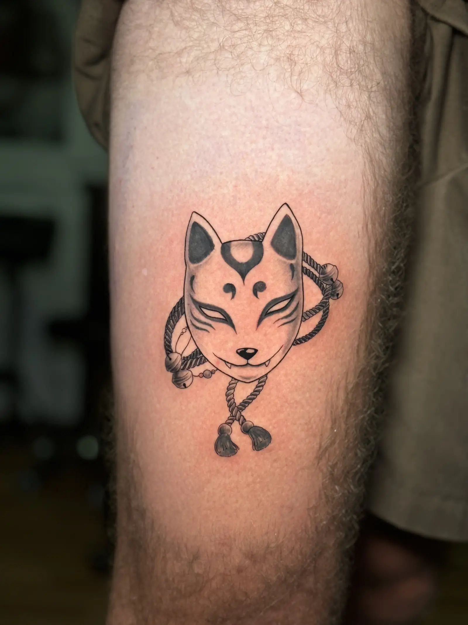 Tatuaje japonés de una máscara de zorro kitsune con cuerda en el muslo, hecho en Cartagena