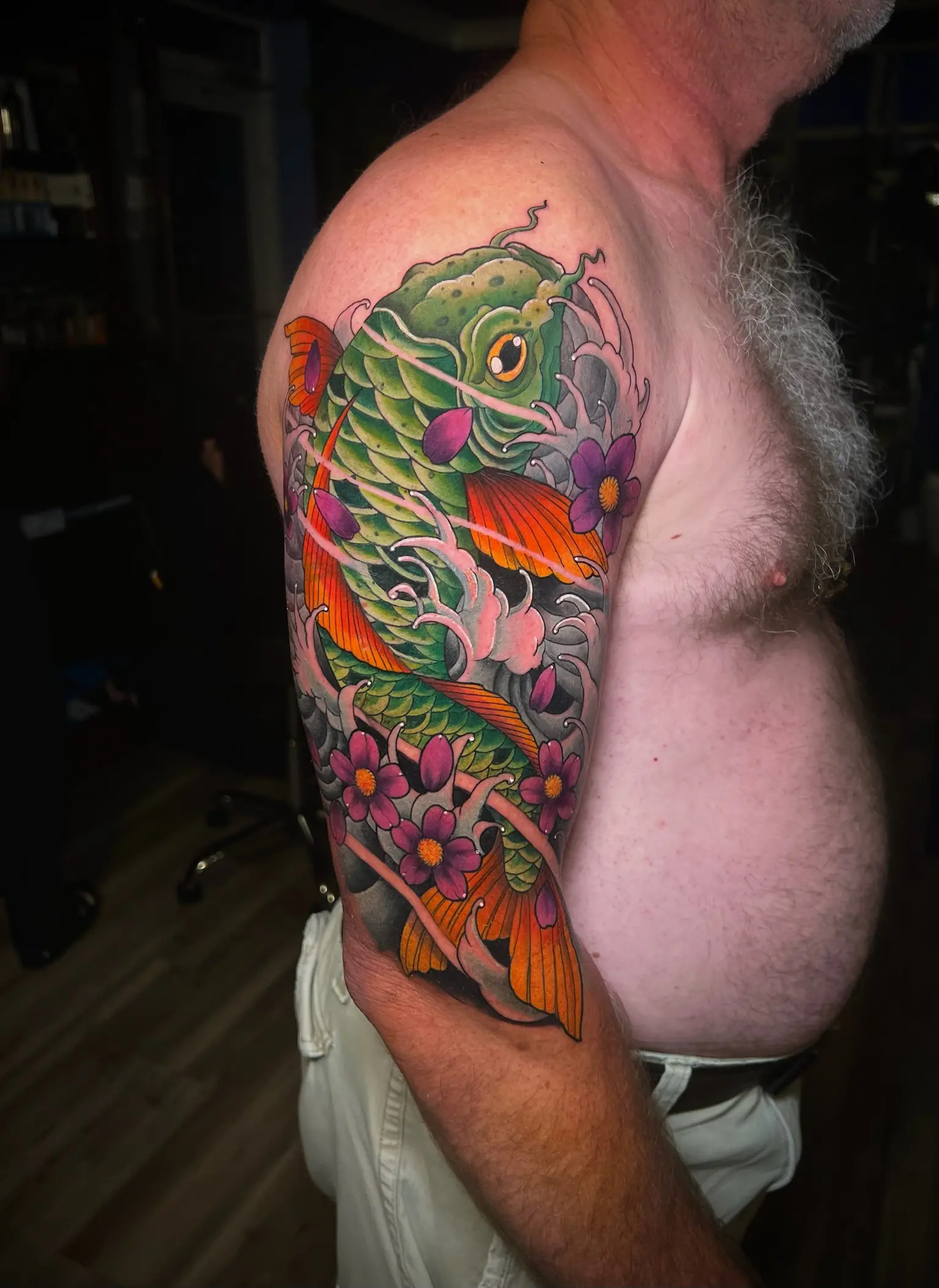 Tatuaje japonés a color de un pez koi con flores de cerezo en el brazo, hecho en Cartagena