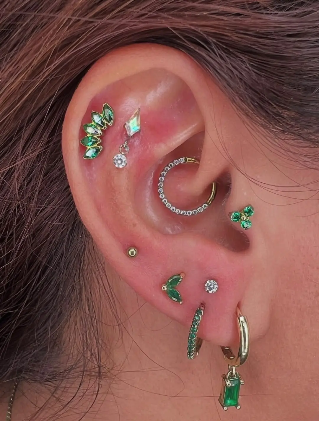 Piercing en la oreja con joyería de titanio de grado implante y piedras verdes, hecho en Cartagena