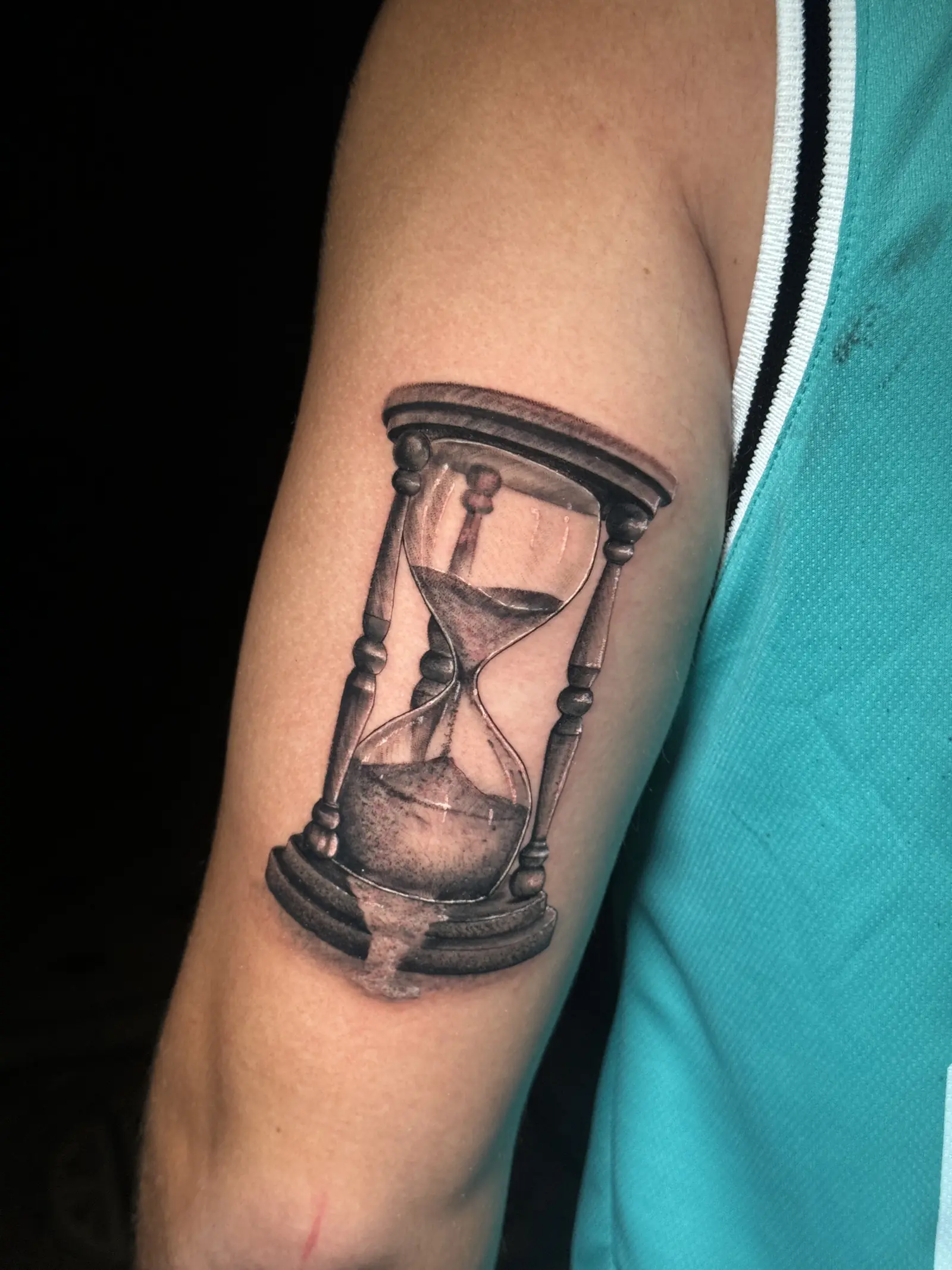 Tatuaje realista en blanco y negro de un reloj de arena en el brazo, hecho en Cartagena