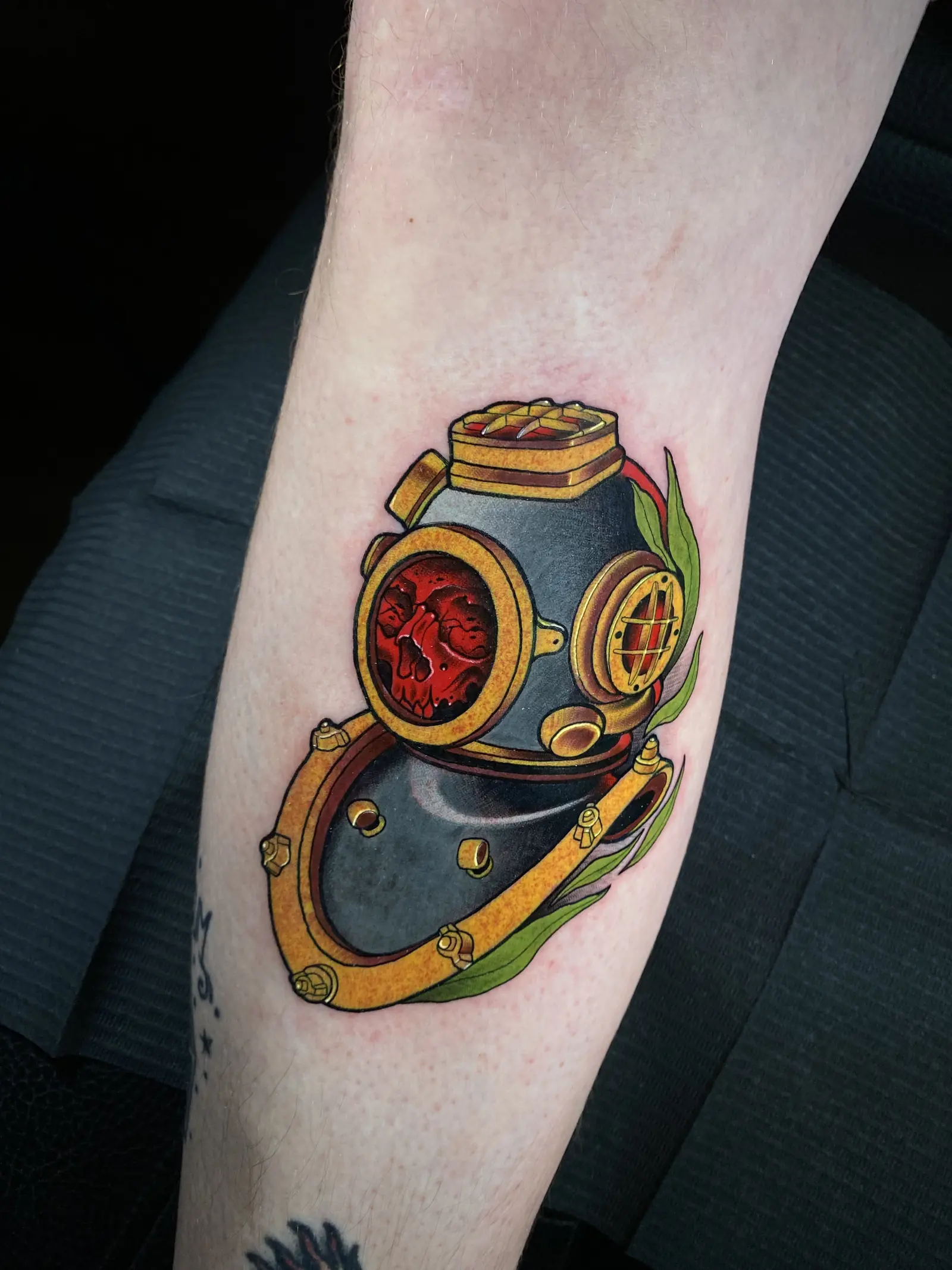 Tatuaje tradicional a color de un casco de buzo con un corazón rojo, hecho en Cartagena