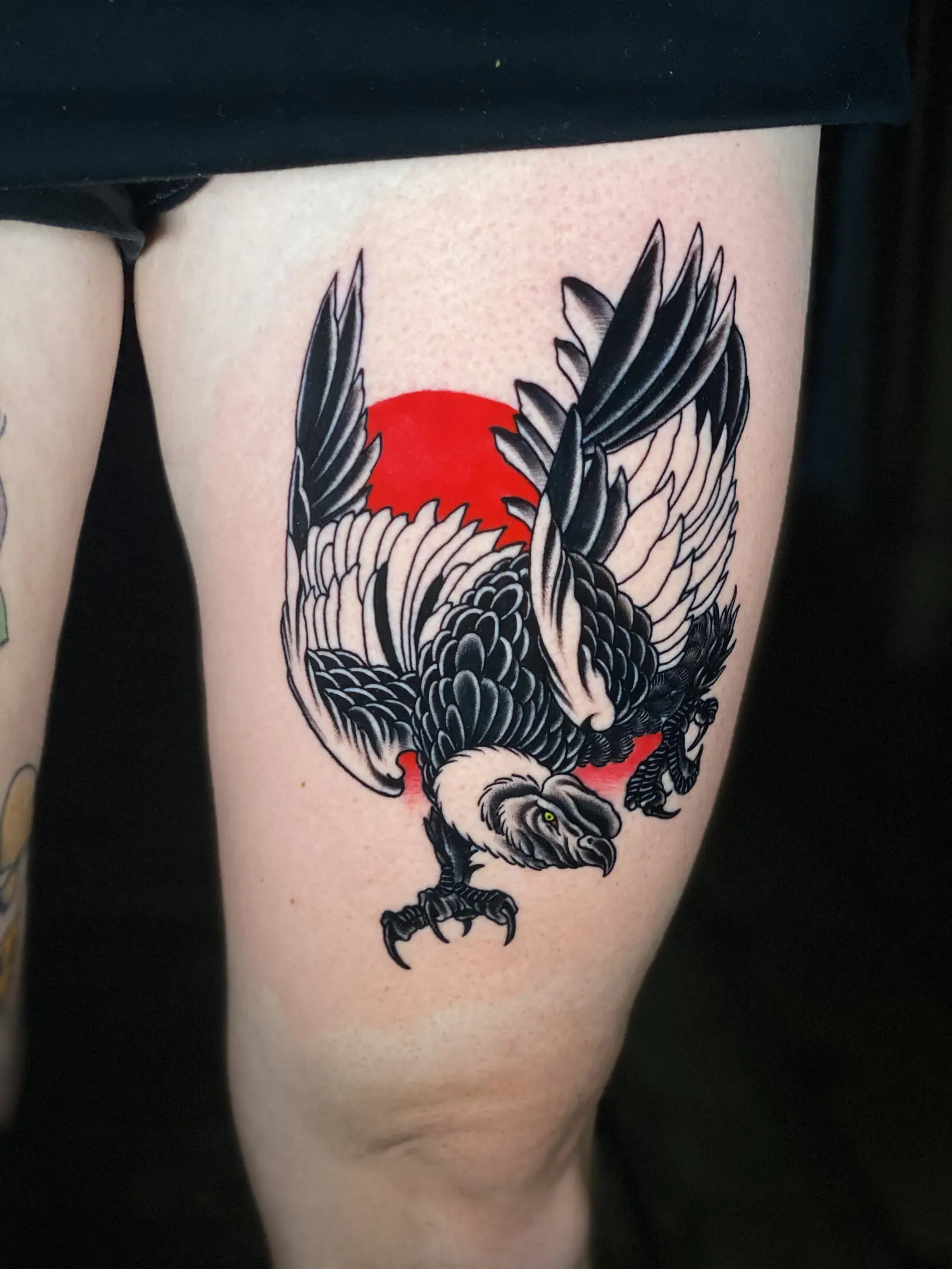 Tatuaje tradicional de un águila con un sol rojo en el muslo, hecho en Cartagena
